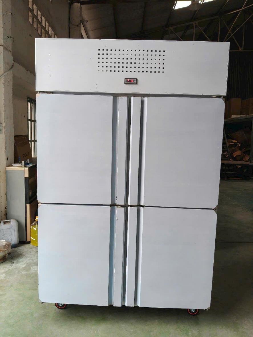 Đầu bếp đang sắp xếp thực phẩm vào tủ đông công nghiệp, thể hiện sự chuyên nghiệp và hiệu quả.