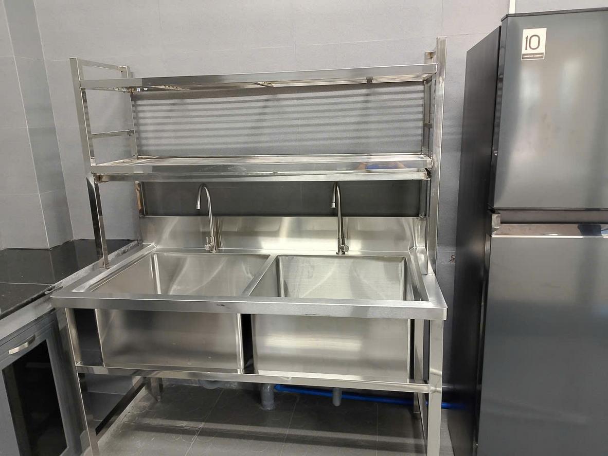 Bảng so sánh trực quan các tiêu chí: Độ bền, Vệ sinh, Chịu nhiệt, Thẩm mỹ, Giá thành của Inox, Gỗ và Đá.