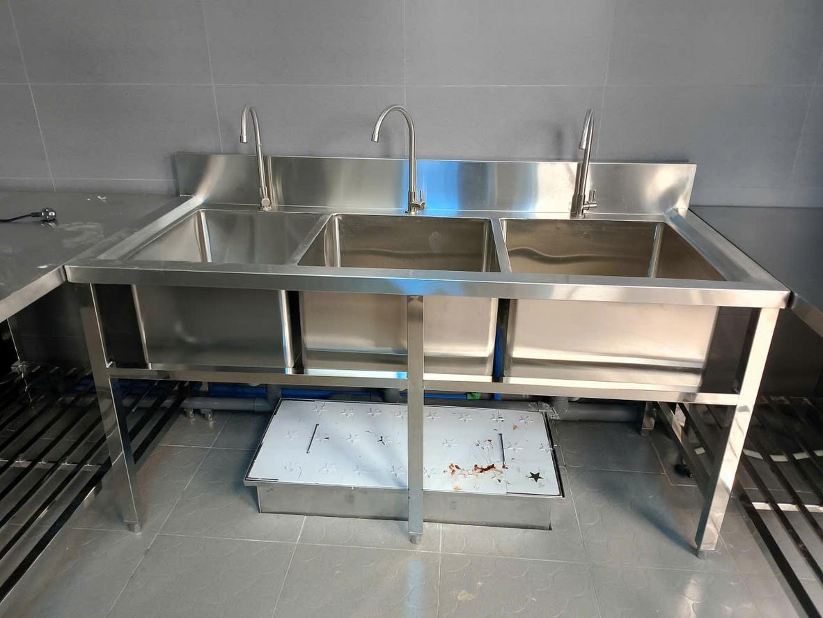 Bộ ảnh gồm 3 hình: một góc bếp gia đình dùng bàn inox, một khu bếp nhà hàng và một bếp ăn công nghiệp quy mô lớn.