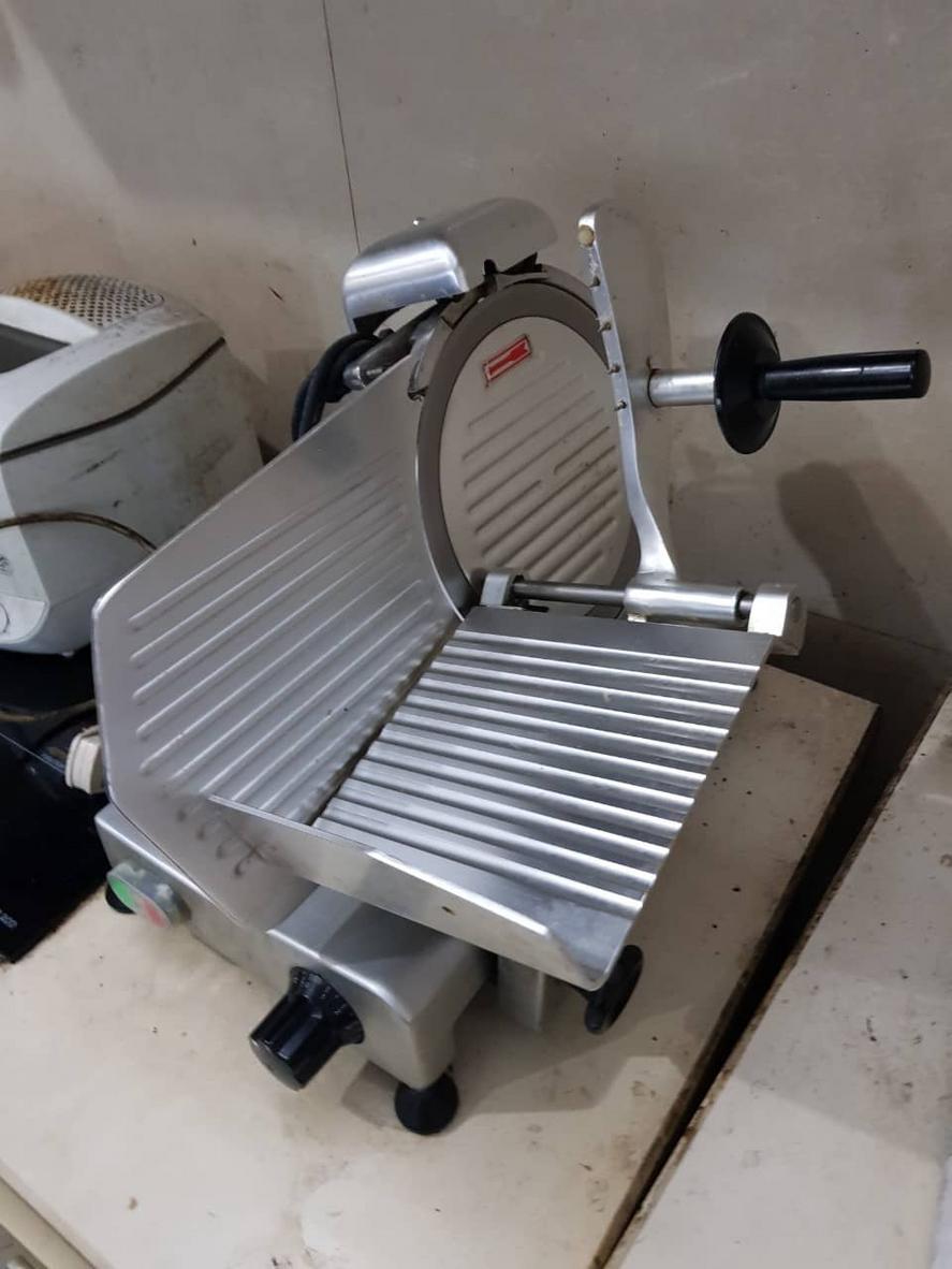 Khu vực sơ chế thịt với máy thái thịt và máy xay thịt trong bếp nhà hàng.