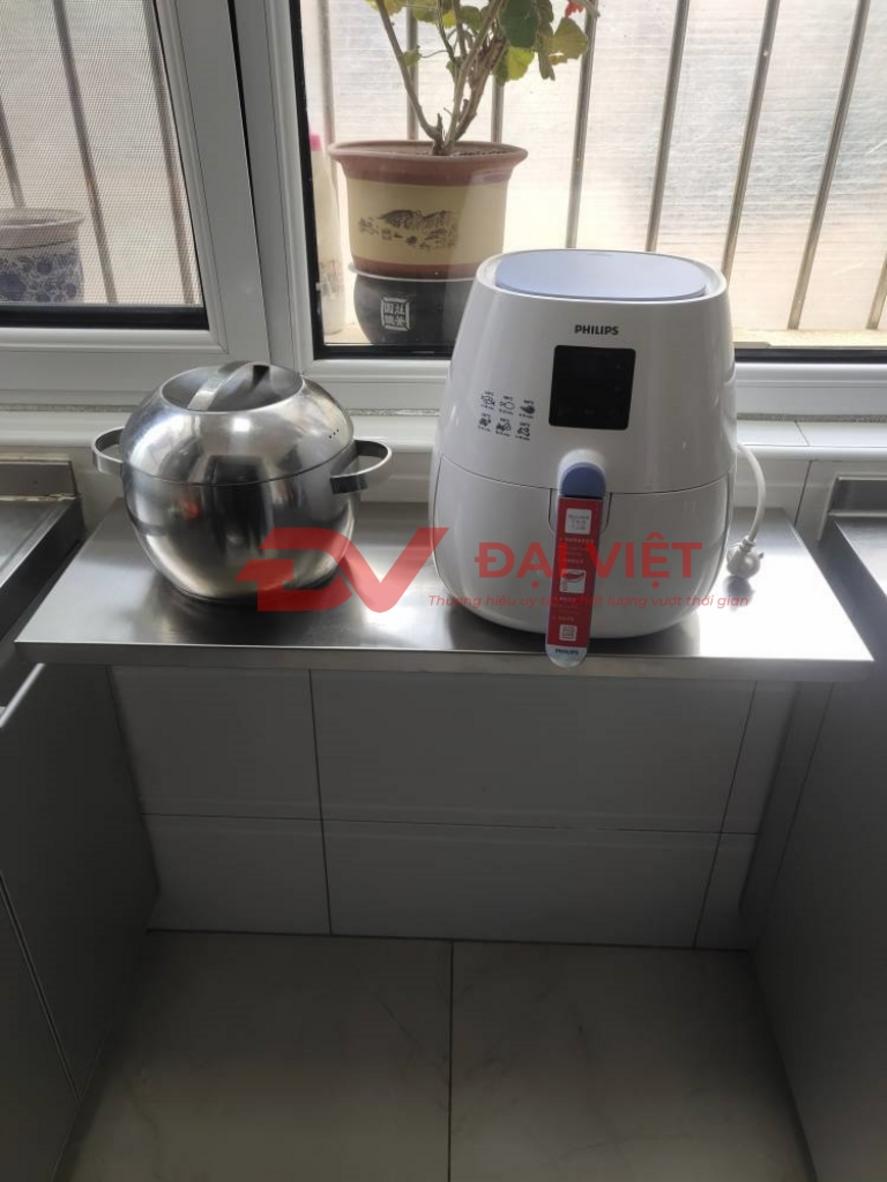 Lau chùi kệ inox bằng khăn ẩm và dung dịch vệ sinh chuyên dụng.