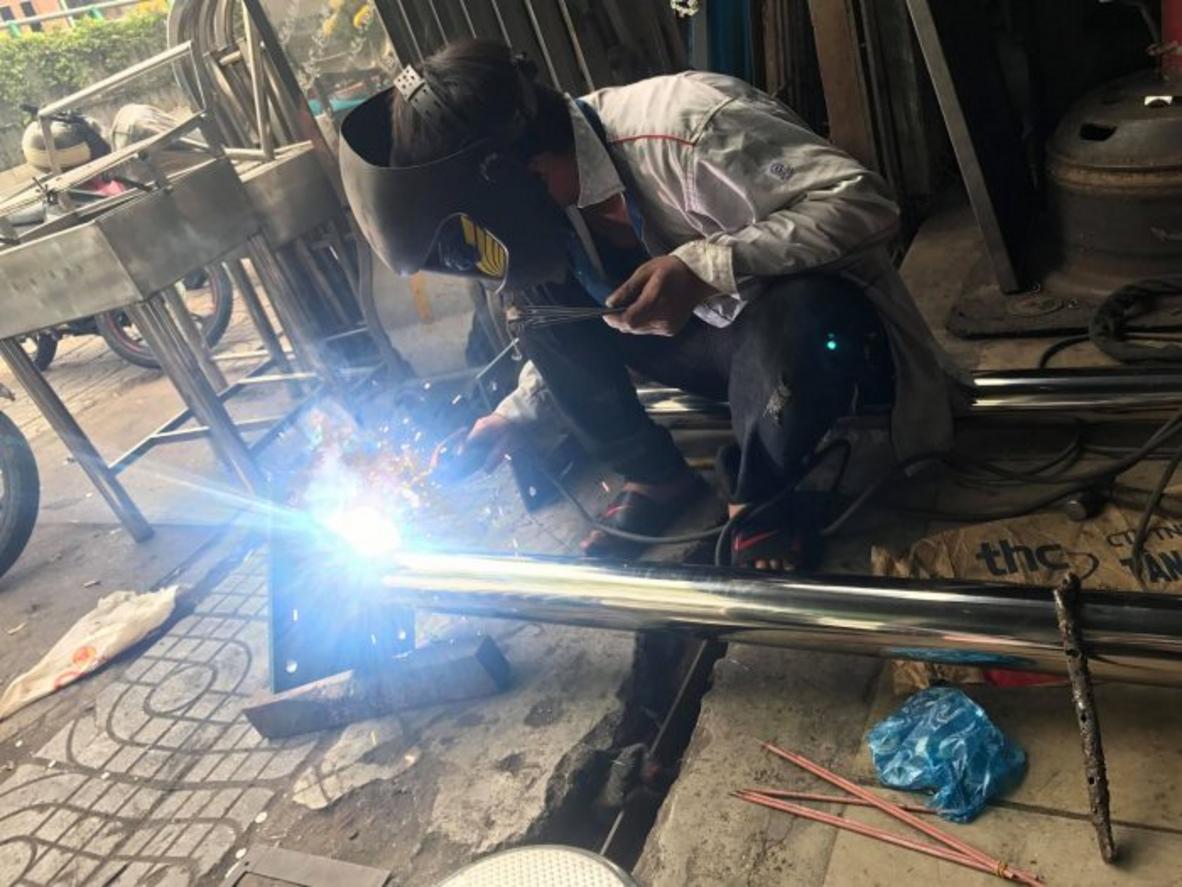 Bàn ra đồ và ốp inox tường giúp khu nấu sạch, dễ vệ sinh và vận hành nhịp nhàng.